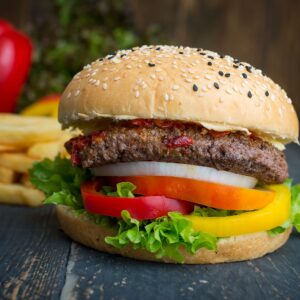 Appetizing cheeseburger with lettuce, tomatoes, onion, and fries. Ideal for food lovers.