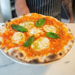 Close-up of a freshly baked Margherita pizza topped with basil leaves, ready to savor.